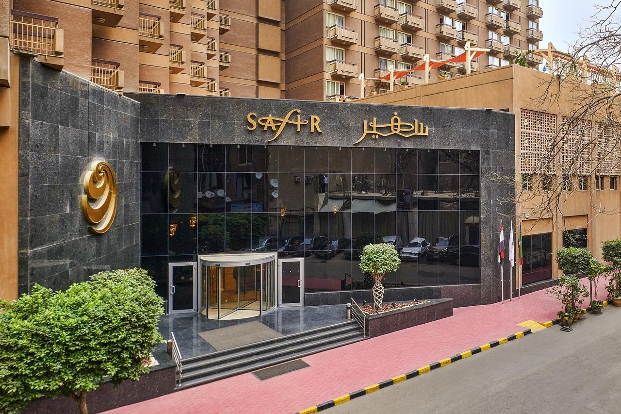 Safir Hotel Cairo Giza Exterior foto The photo depicts the entrance of a modern building, which appears to be a hotel or a commercial establishment. The facade features a large glass front with reflective surfaces. Above the entrance, there is a prominent sign displaying the name of the