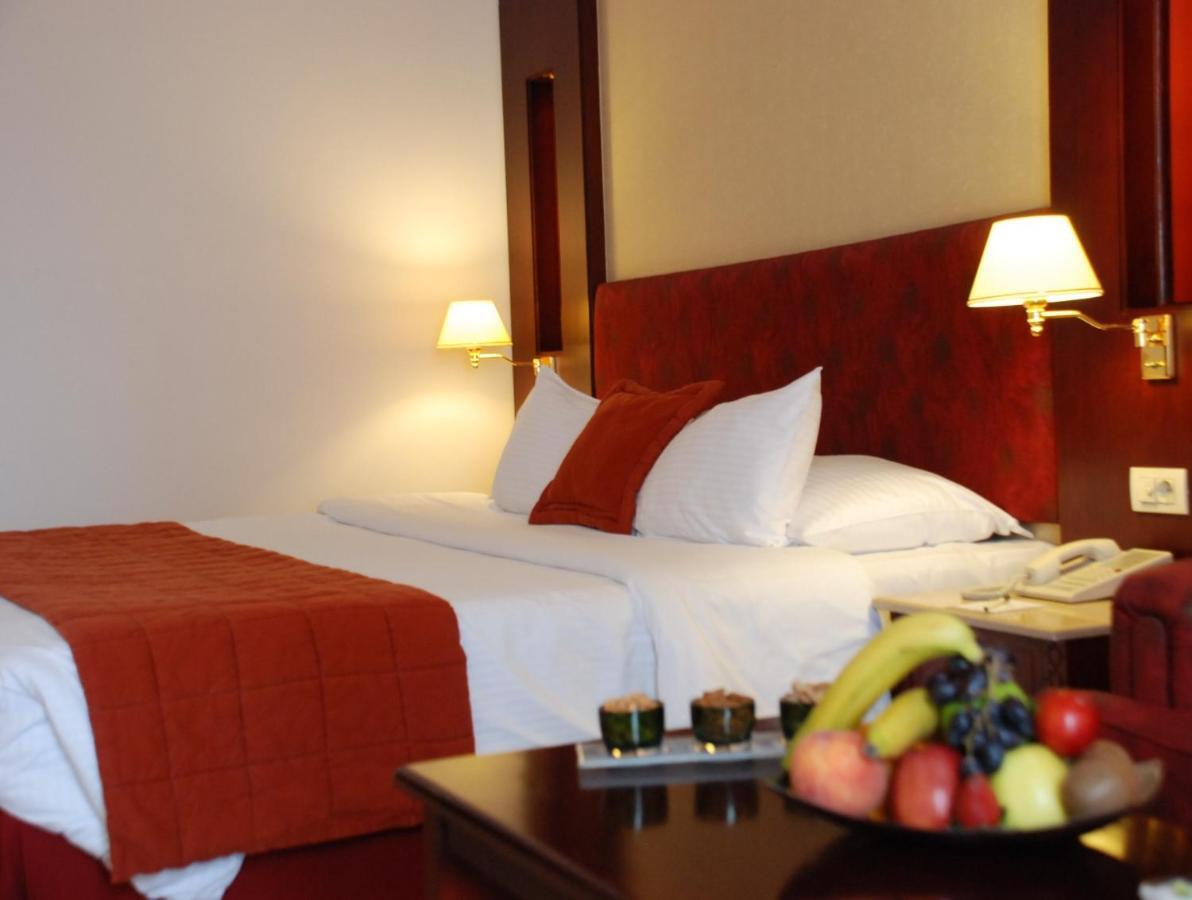 Safir Hotel Cairo Giza Quarto foto The photo shows the interior of a hotel room featuring two beds with white bedding and an orange throw blanket. There are decorative pillows on the beds. The walls are designed in warm tones, and there are two bedside lamps providing soft illuminatio